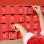 little girl in christmas outfit in front of an advent calendar