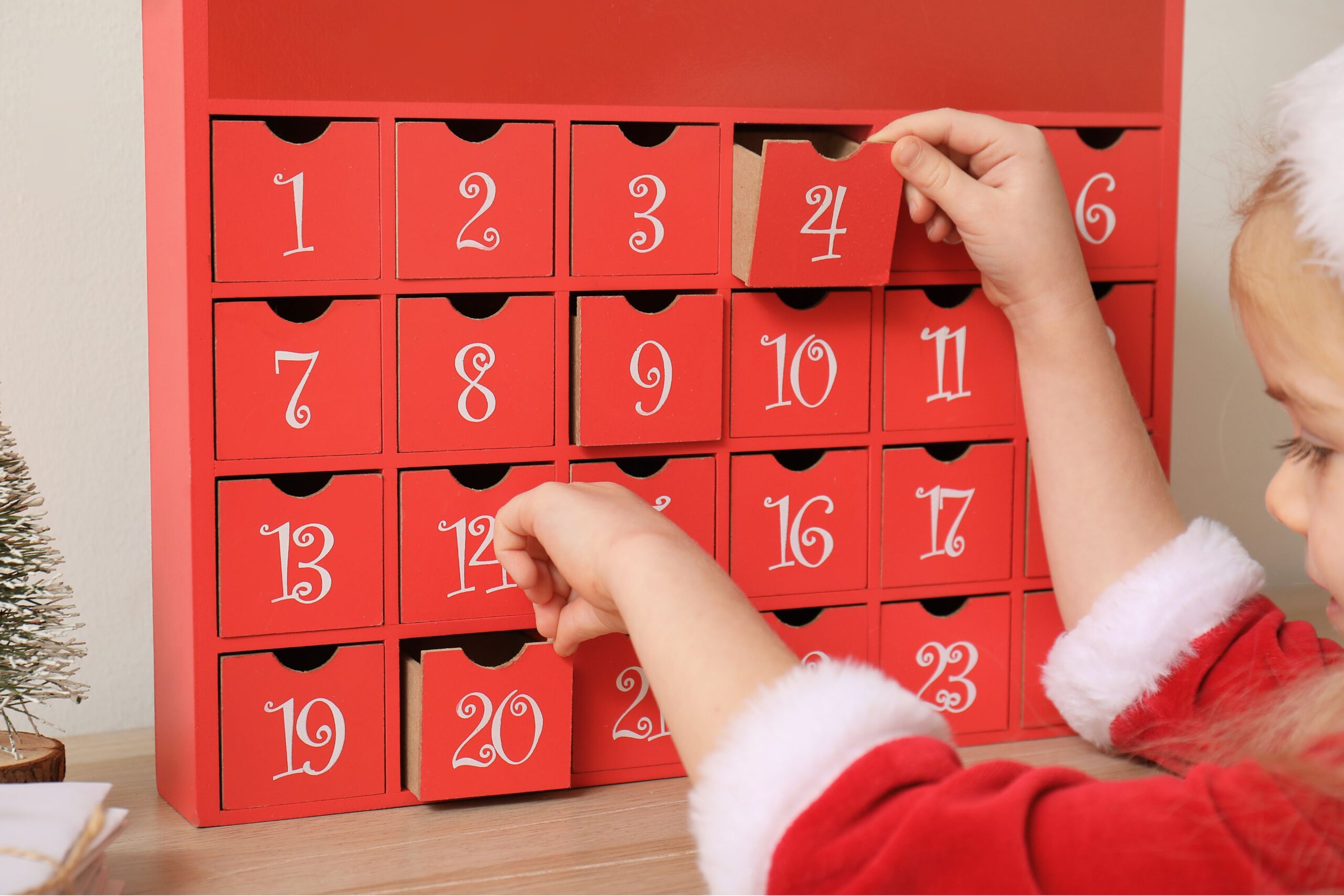 little girl in christmas outfit in front of an advent calendar