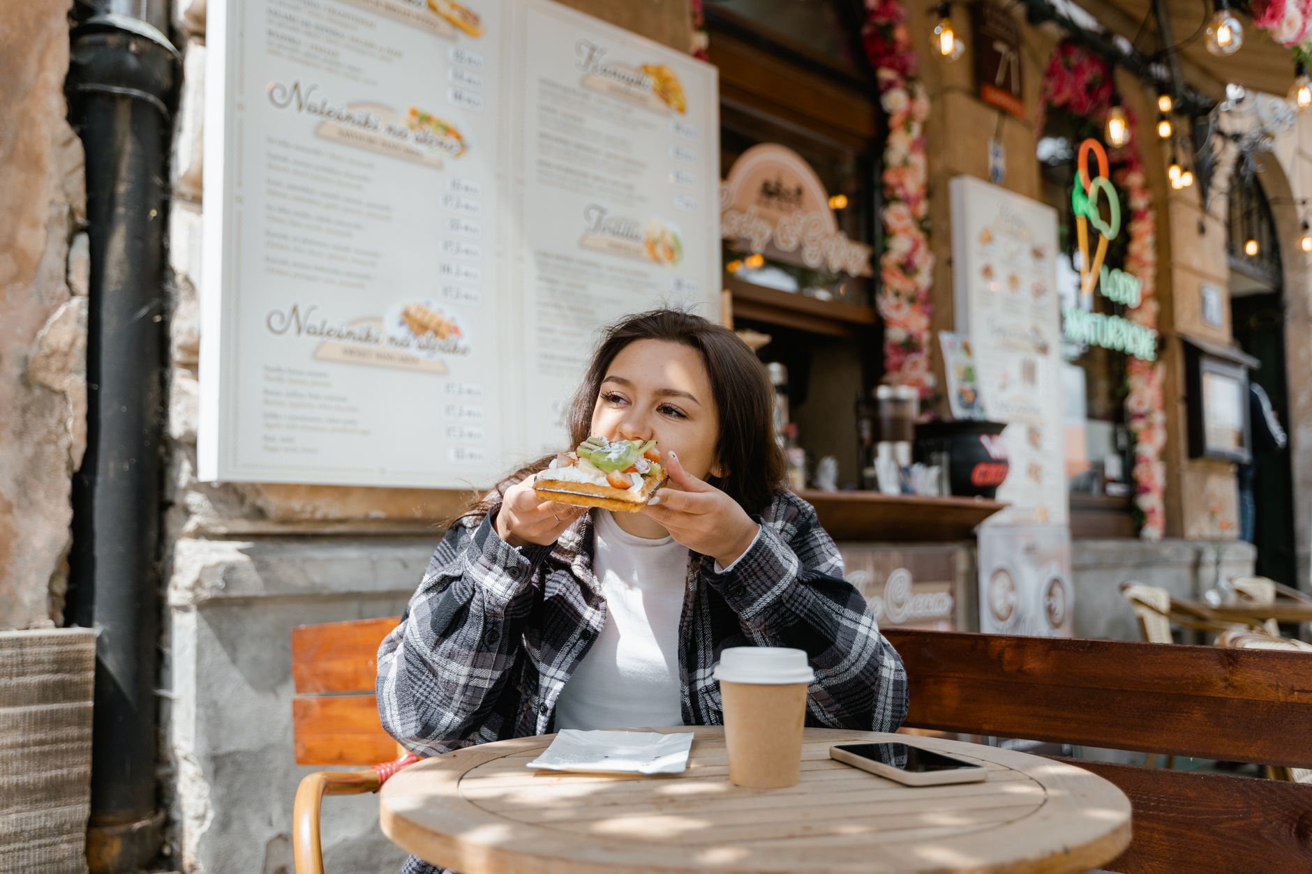 A woman enjoying a meal at a gluten-free Paris bistro, reviewing the menu with a relaxed expression