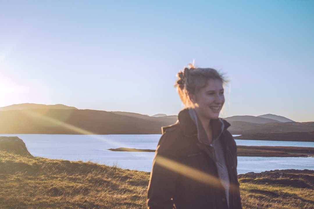 A woman stands in soft June daylight during a Nordic summer morning, her face turned toward the light in a moment of calm wellbeing.