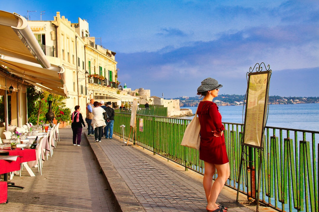 A woman strolls through a sunlit alley in one of the most charming EU beach towns in late June