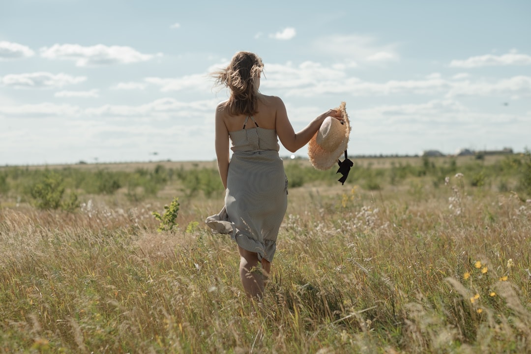 A woman wearing a flowing natural linen dress from one of Europe's leading linen brands, standing in warm summer light