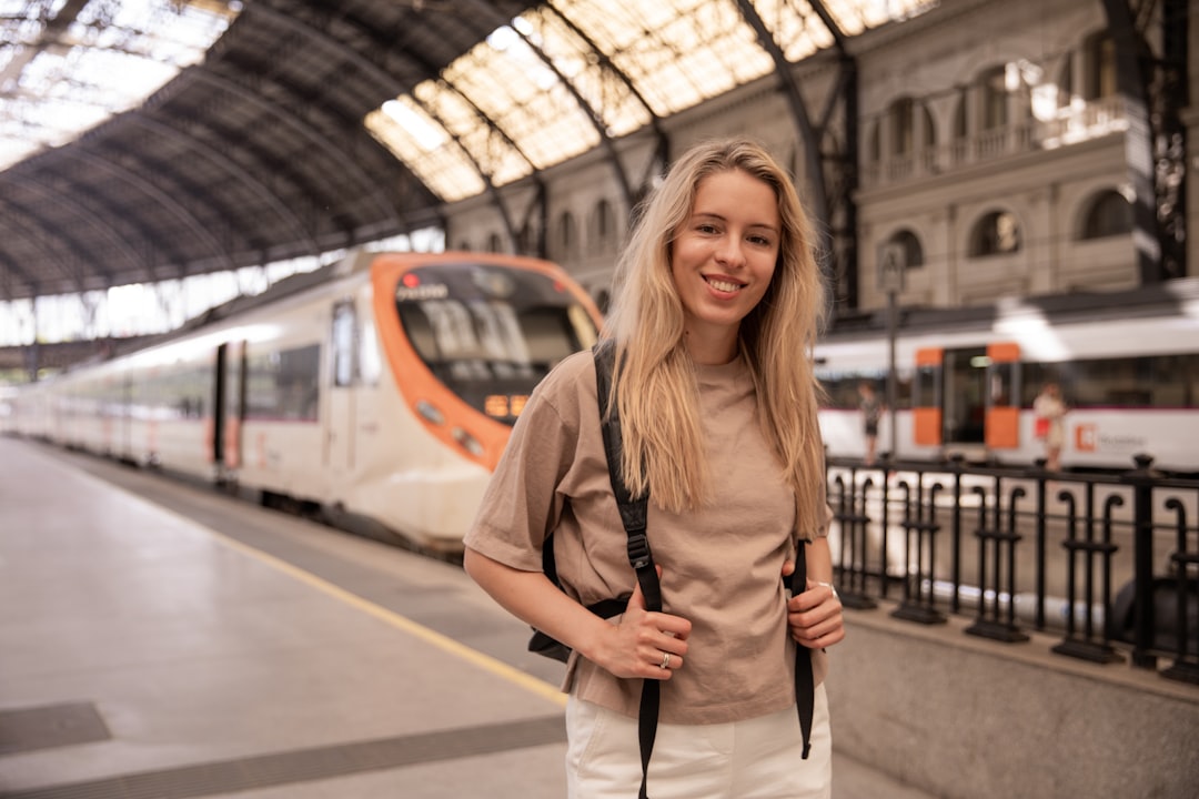 A young woman boarding a train in Europe holding her phone with rail passes ready to show