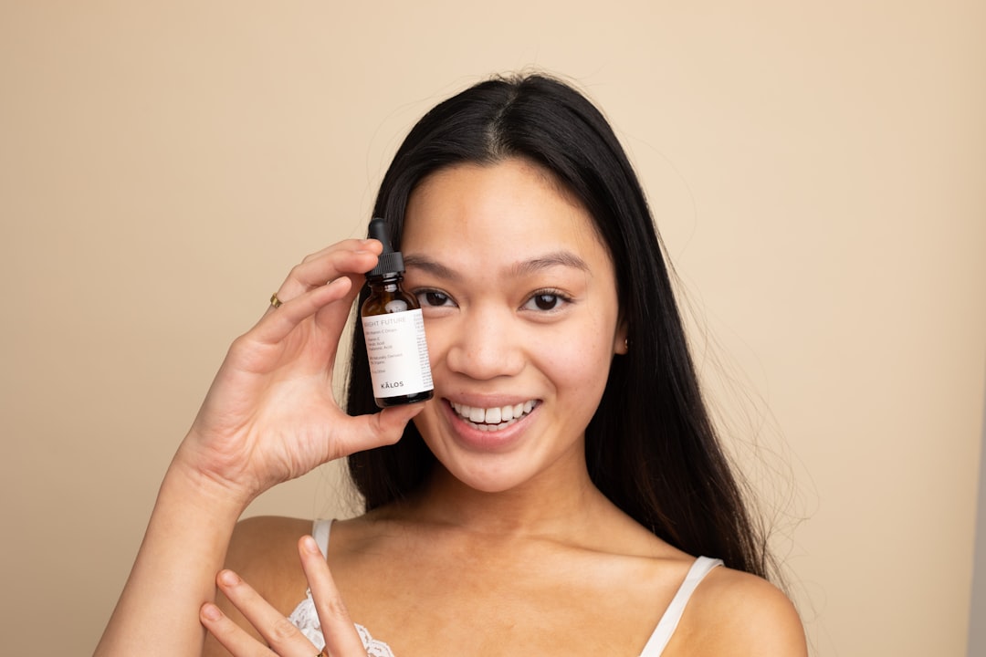 A woman carefully applying a serum containing EU skincare ingredients in a minimalist bathroom setting