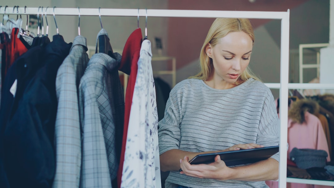 A woman examines a certification label on a garment while shopping for circular fashion brands in a European retail store.
