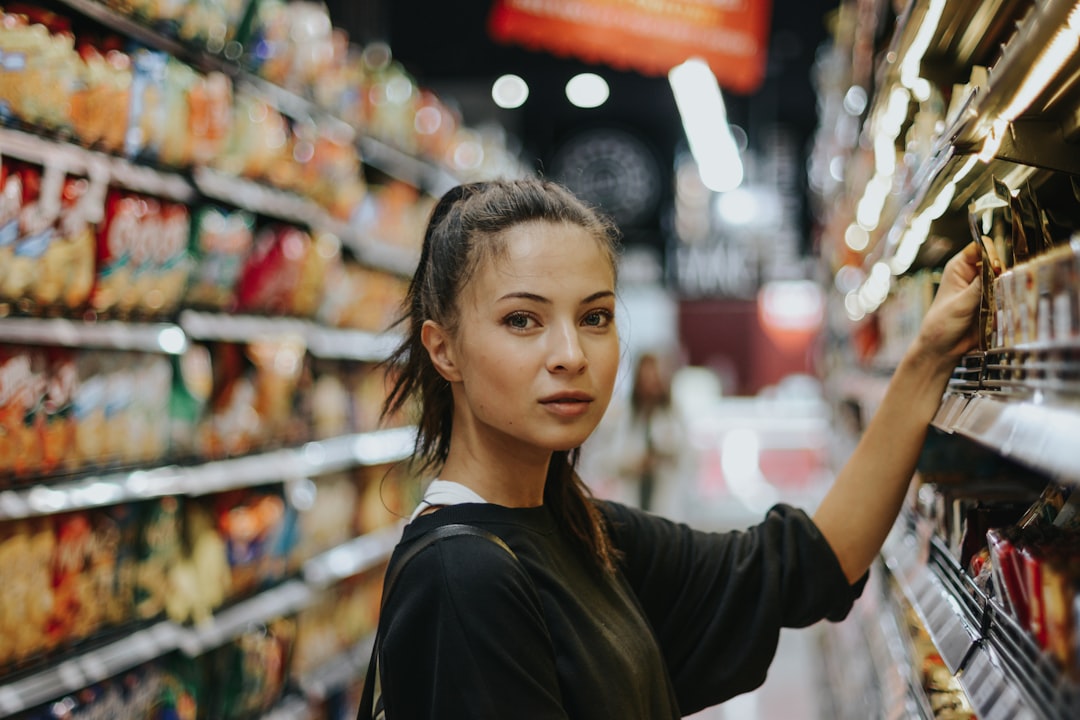 A woman carefully reading the packaging of an EU Ecolabel certified household cleaning product in a supermarket aisle.