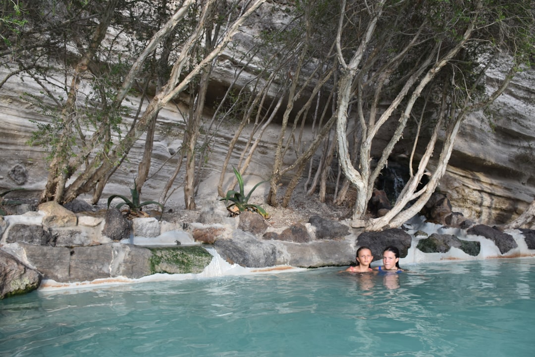 A woman relaxing in a certified thermal spa pool surrounded by historic stone architecture in Europe