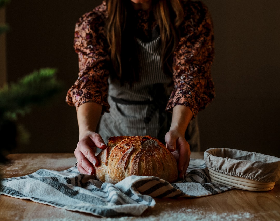A baker proudly presents a rustic wheat-free bread loaf in a traditional European artisan bakery