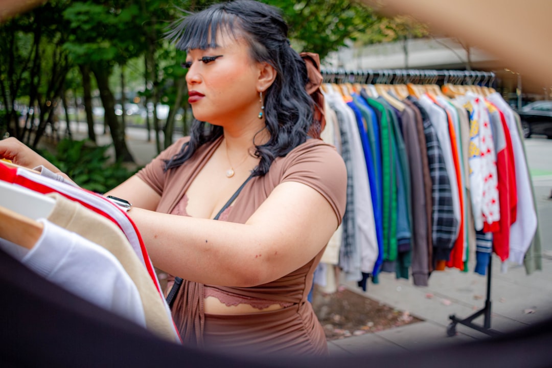 A woman reviews garments at an EU circular fashion sample sale, looking for certified-organic pieces at reduced prices.