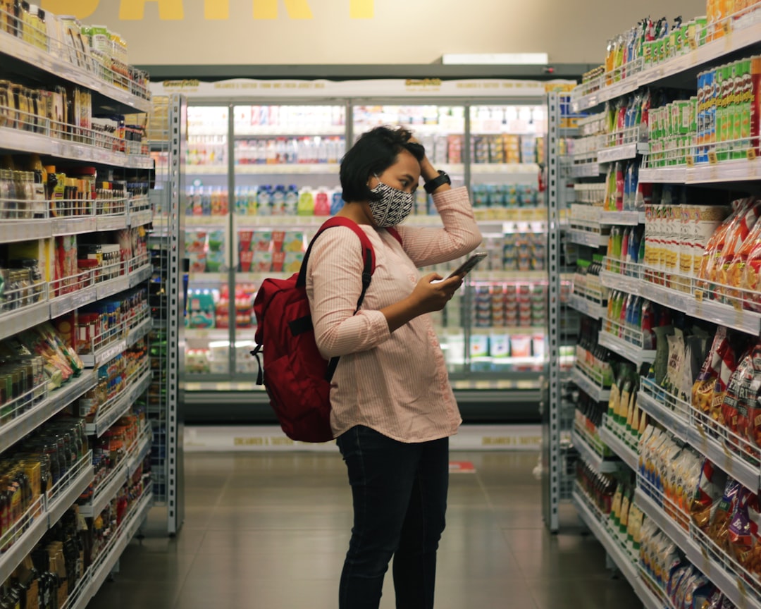 A woman carefully reading the EU Ecolabel flower logo on a cleaning product in a European supermarket aisle