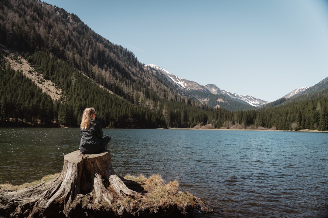 A woman gliding through the clear waters of an EU lakeside destination surrounded by mountain scenery